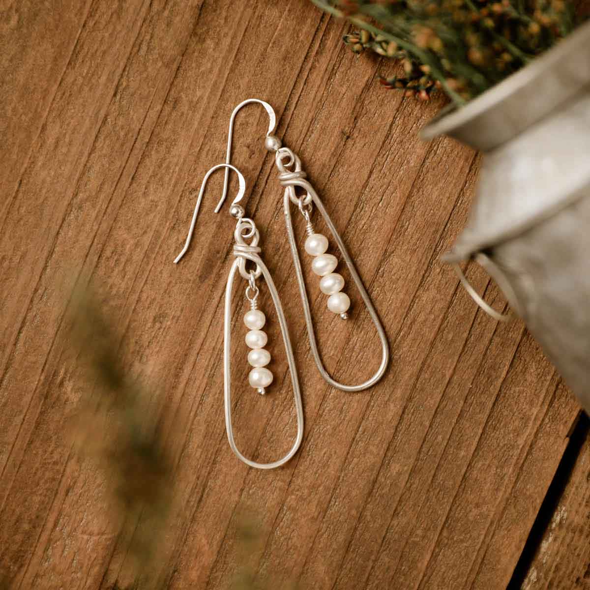 a mother's love pearl sterling silver earrings on a wood background