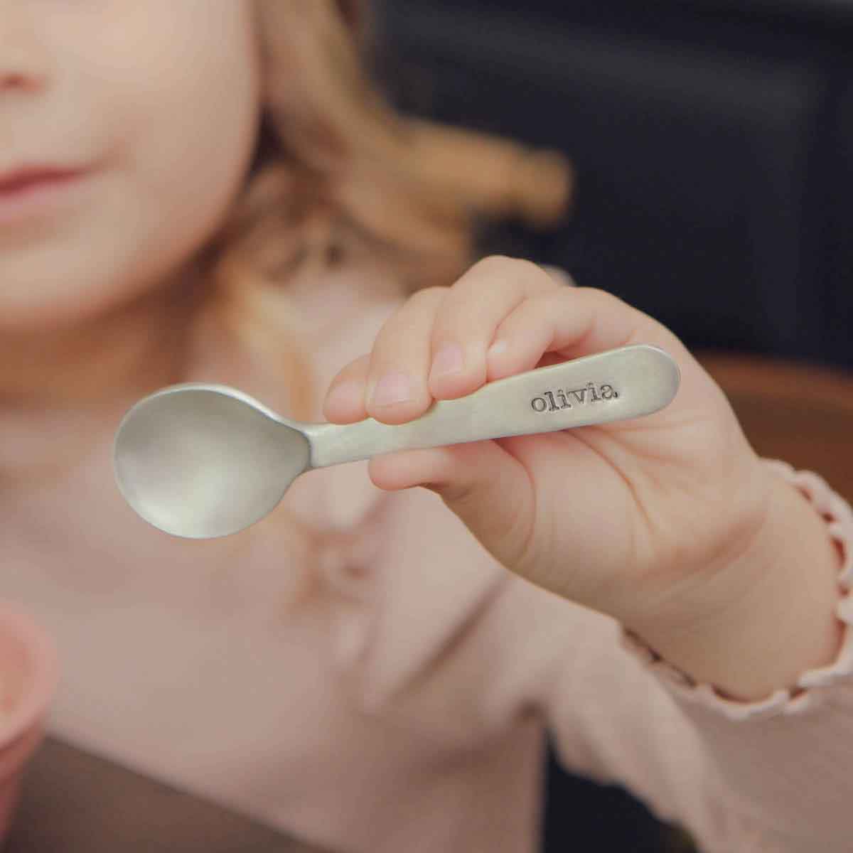 baby girl holding an Adorable Baby’s First Spoon