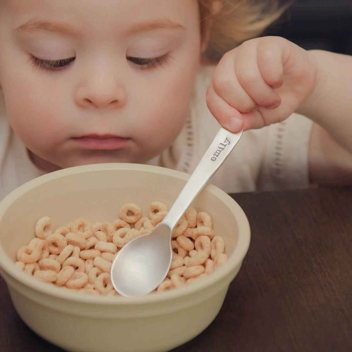 baby girl holding an Adorable Baby’s First Spoon