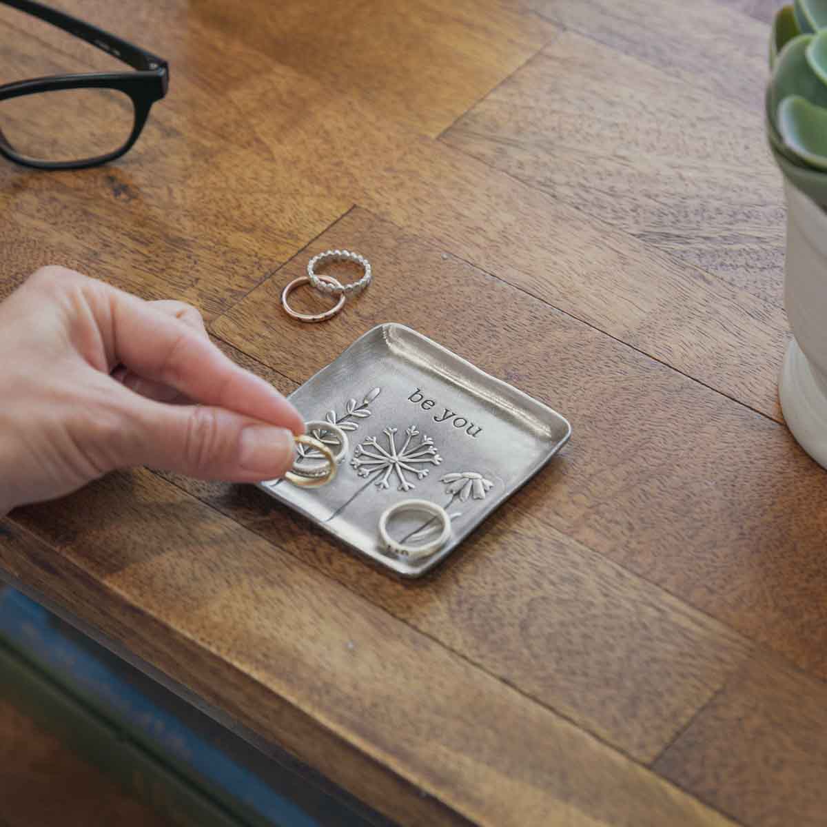 be you pewter keepsake dish on a wooden table with rings on it