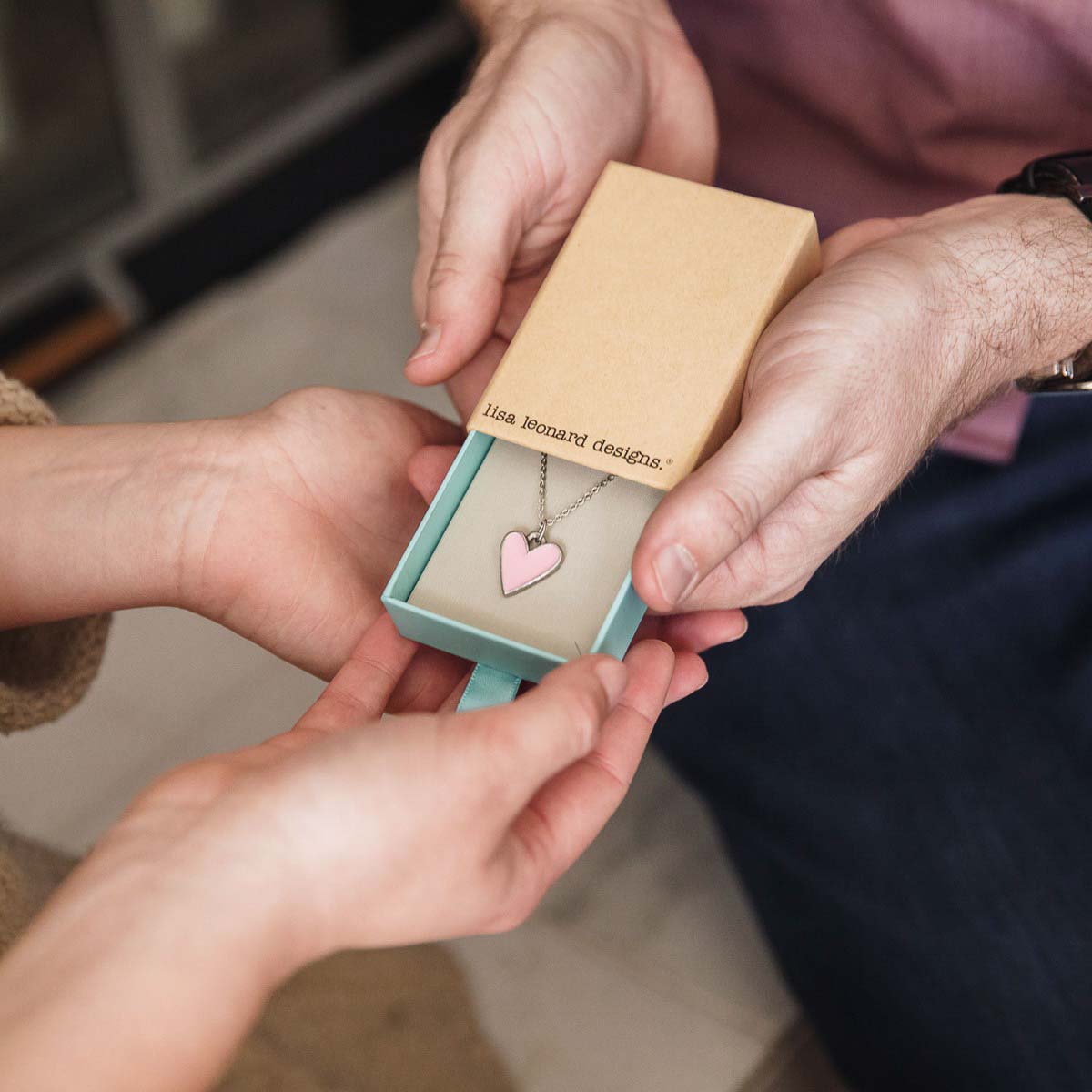 Girl holding her Brave Love heart necklace handcrafted in pewter with choice of color epoxy in original packaging