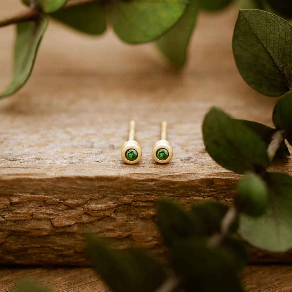 14K yellow gold Dainty Finespun Birthstone Stud Earrings - Small 2mm on a wood background