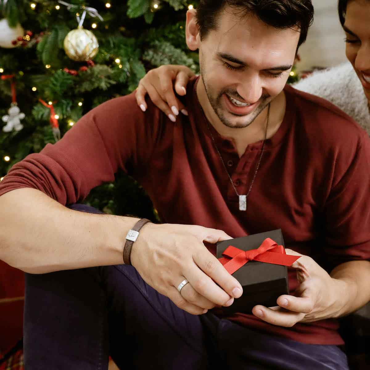 opening a gift from girlfriend in front of christmas tree