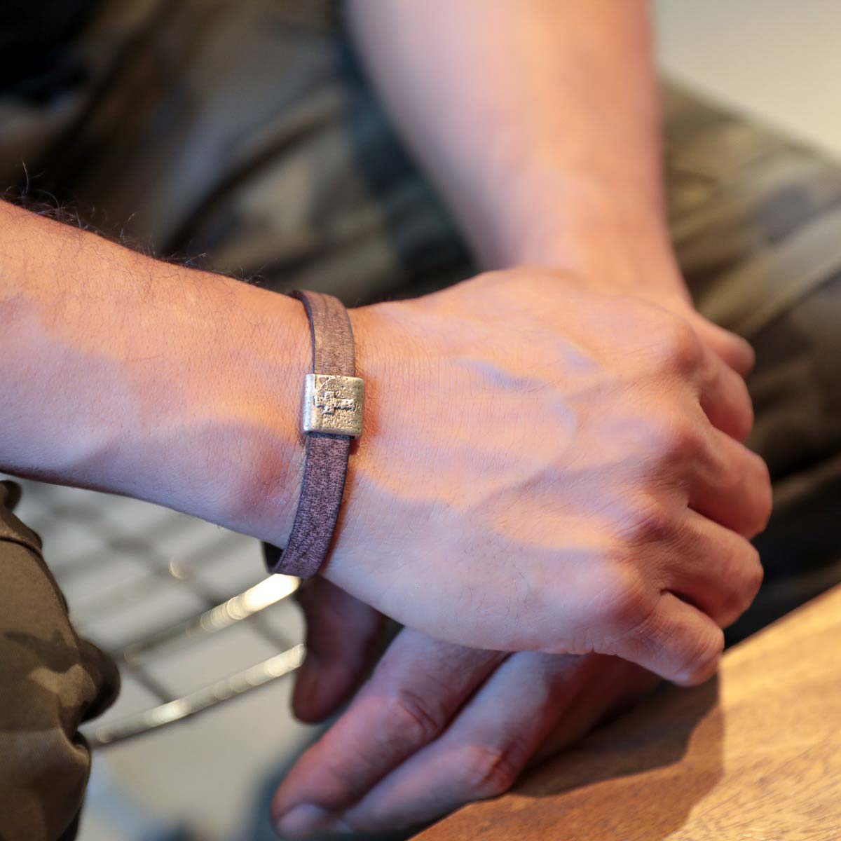 Man wearing Equitable Leather Cross bracelet handcrafted in brown latigo leather with a pewter bead