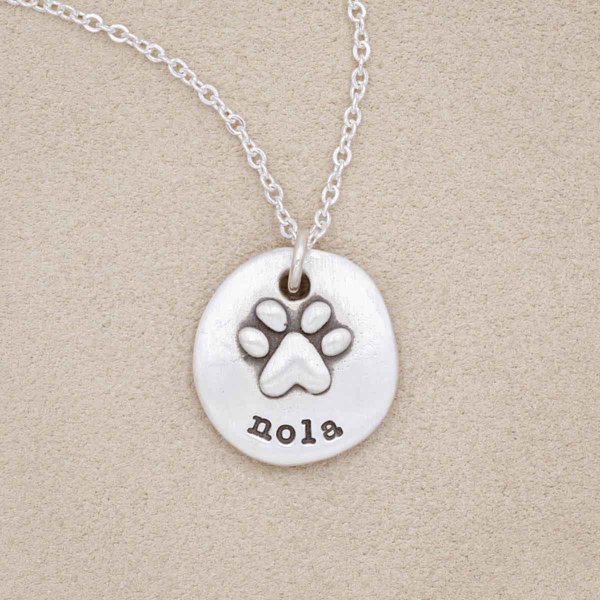 Furry footprint necklace handcrafted in sterling silver with a paw engraved and personalized with a pet's name