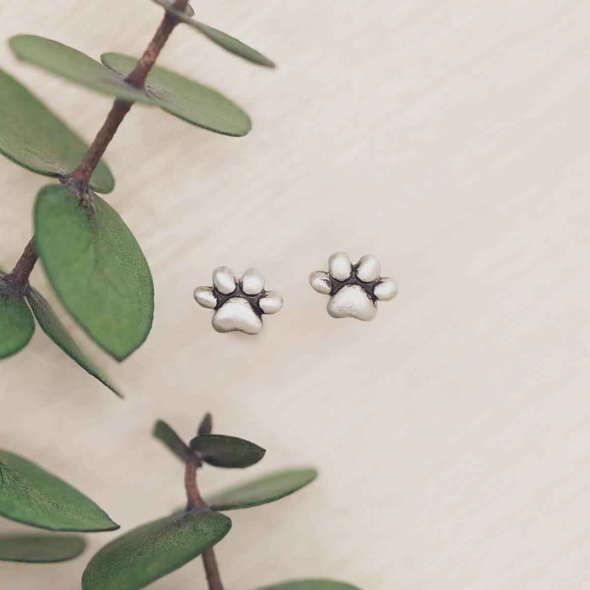 girl holding Furry Footprint Stud Earrings handcrafted in sterling silver