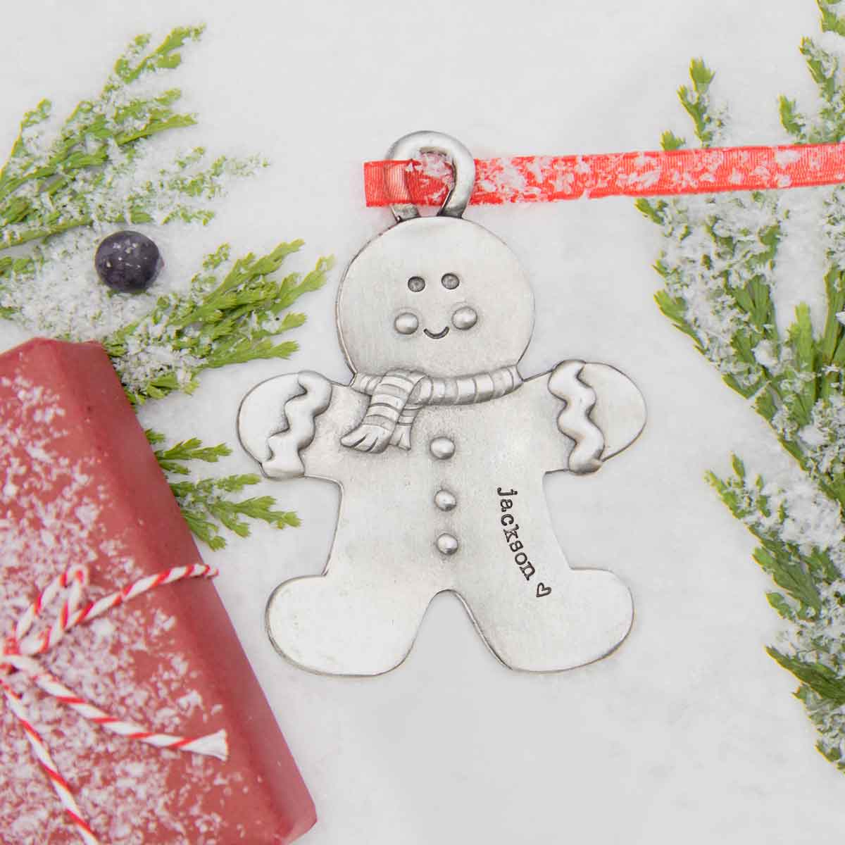 Gingerbread boy ornament hand-molded and cast in fine pewter hung from a sheer red ribbon with a personalized word