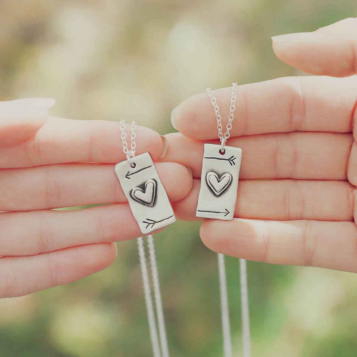 two hands holding the sterling silver i love you necklace set