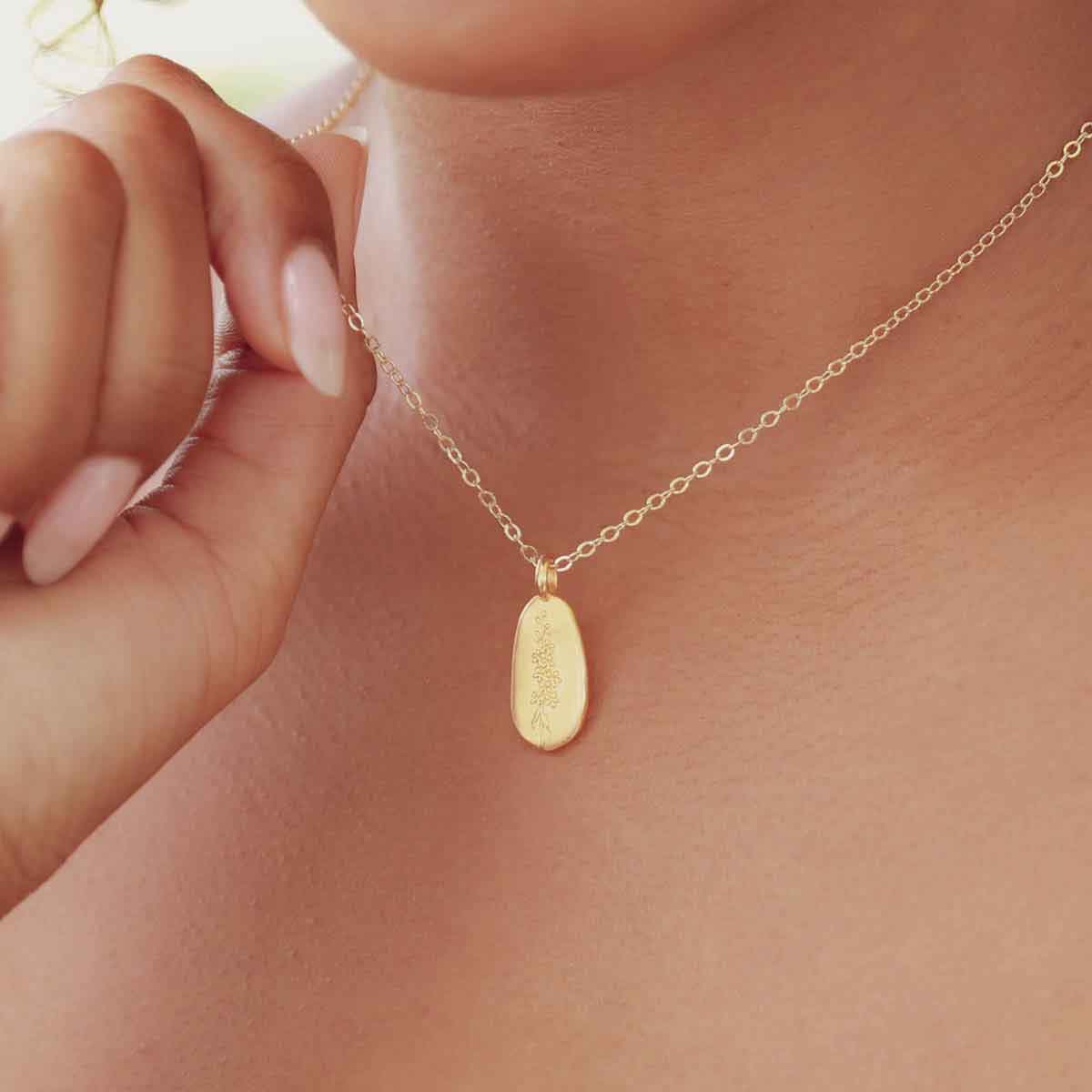 girl holding a gold plated July birth flower necklace with an 18" gold filled link chain