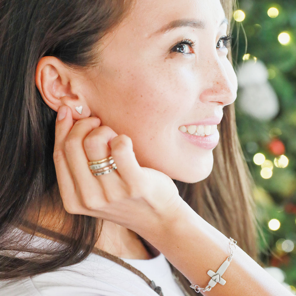 girl wearing sterling silver tiny heart stud earrings with a matte brushed finish