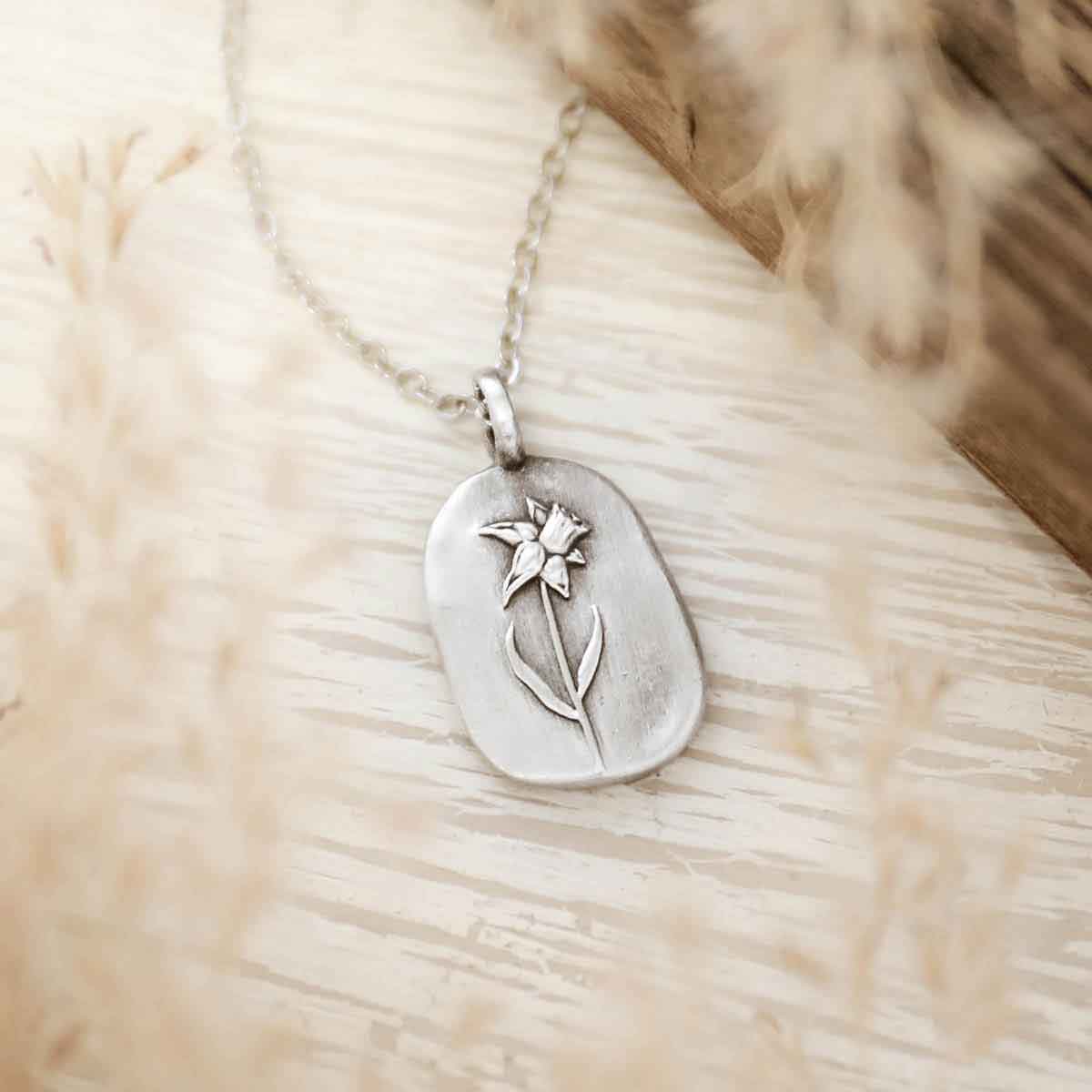girl holding a pewter March Birth Flower necklace with an 18" link chain