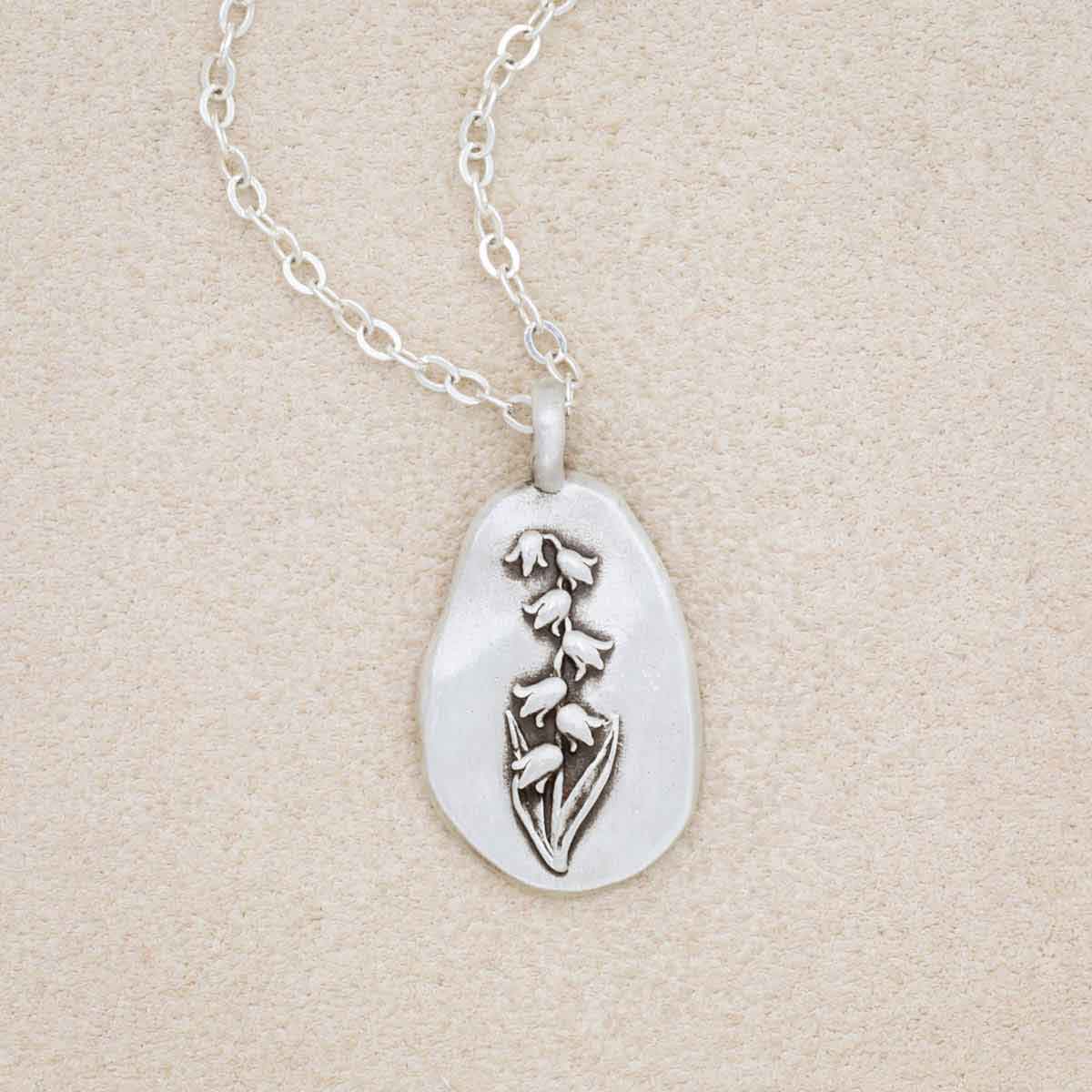 sterling silver May Birth flower necklace, on beige background
