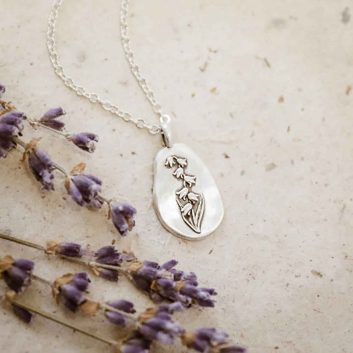 girl holding a sterling silver May Birth flower necklace