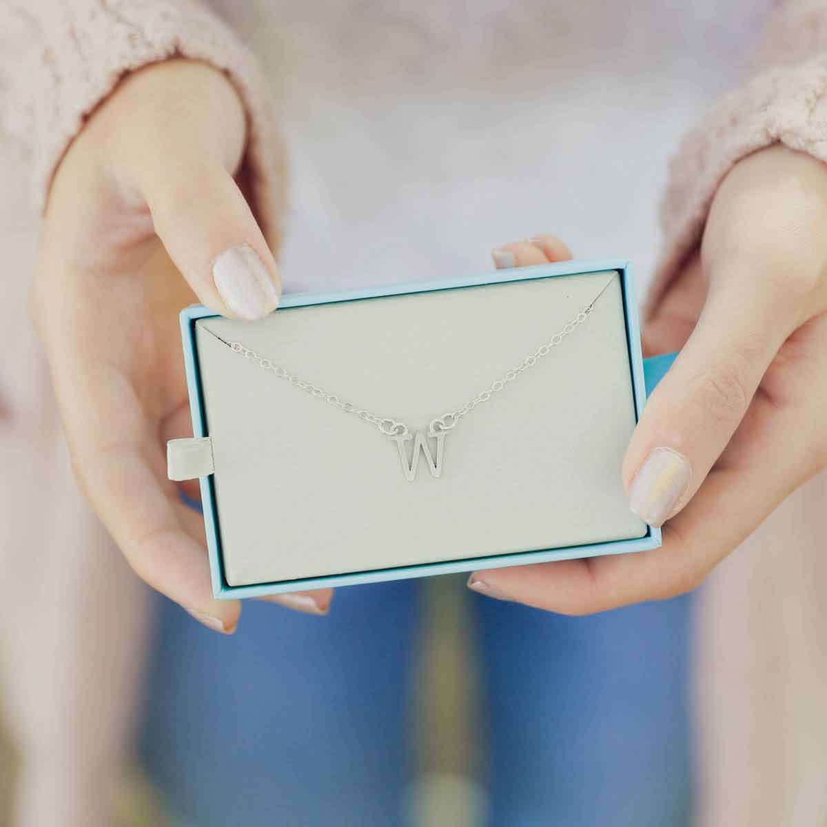 Girl holding a Sterling silver monogram bracelet with a satin finish