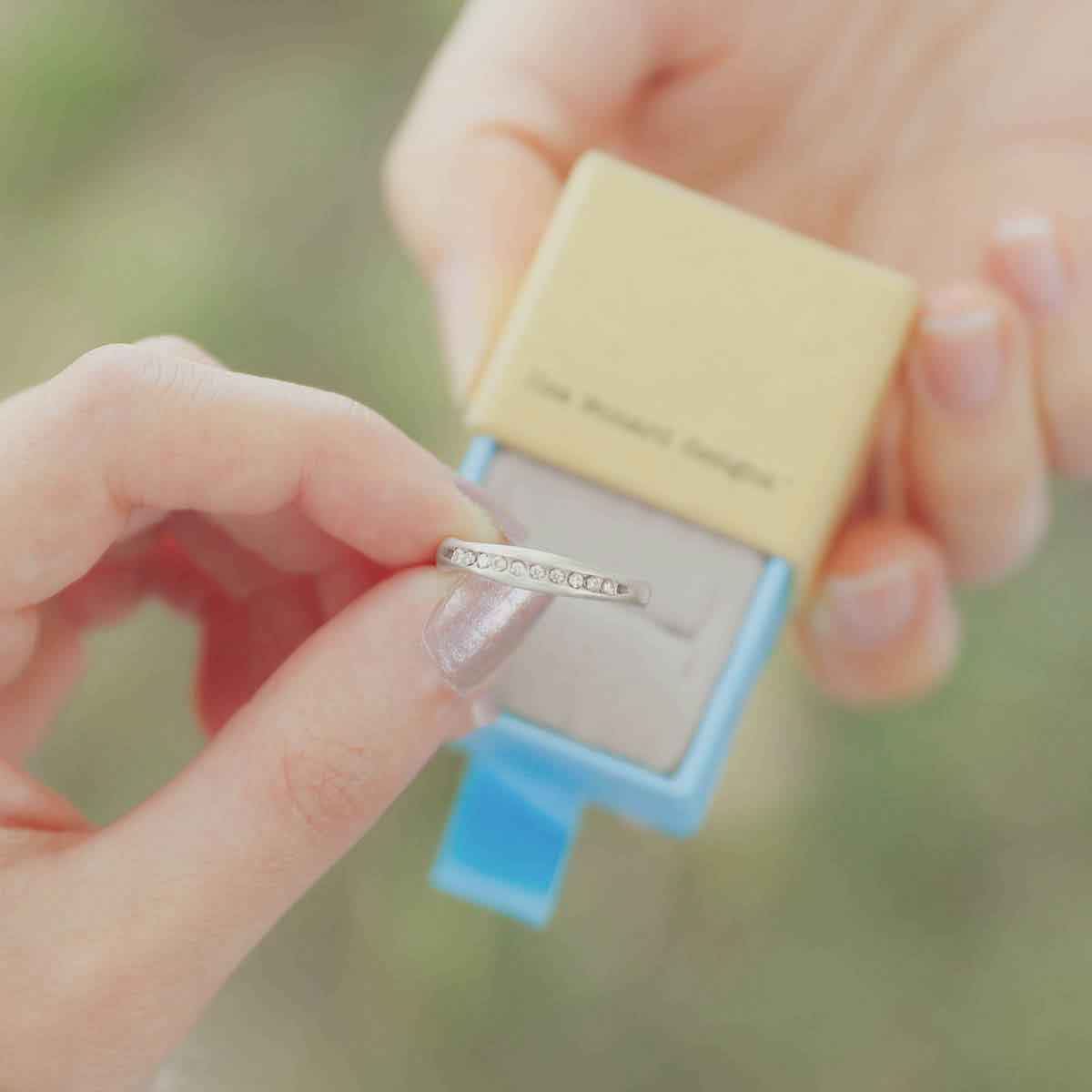 hands holding Passage ring handcrafted in sterling silver and display of 1.5mm cubic zirconias in original packaging