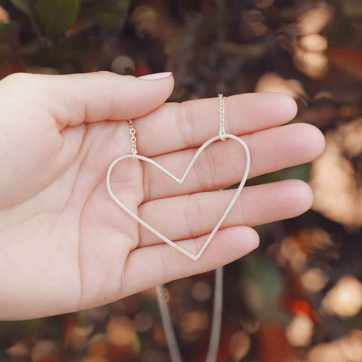 girl holding a Peaceful Heart Necklace handcrafted in sterling silver
