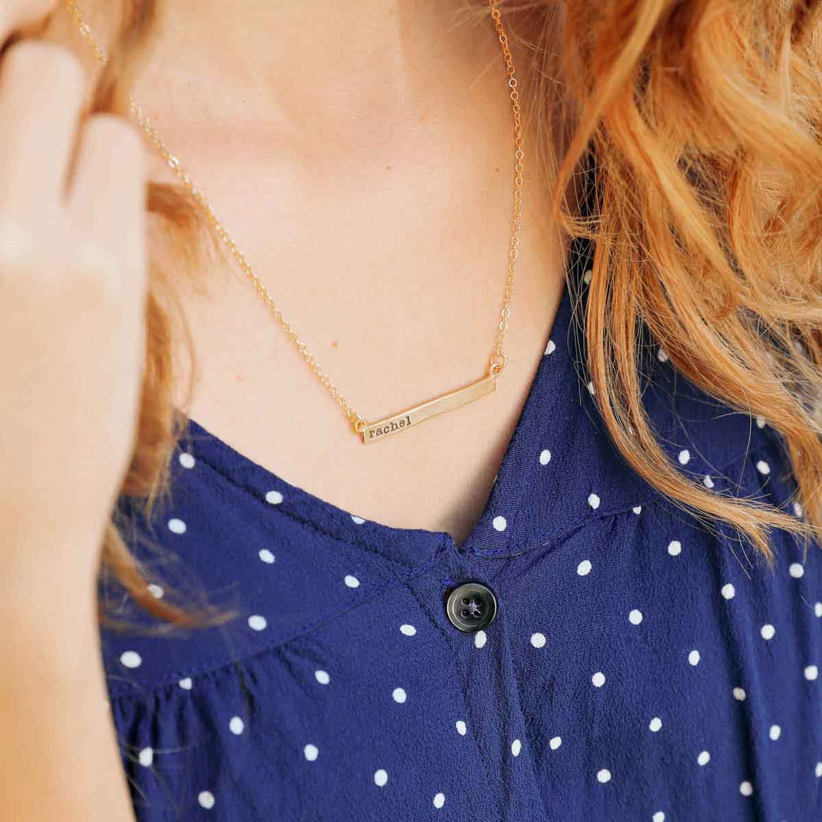 wearing a yellow gold personalized cross bar necklace