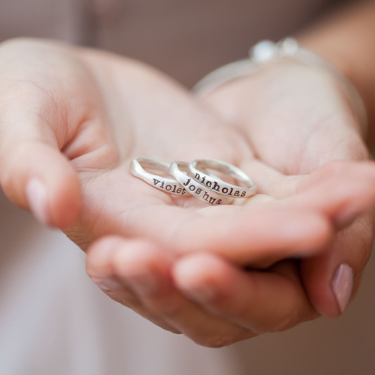 girl holding personalized sterling silver stackable name ring trio