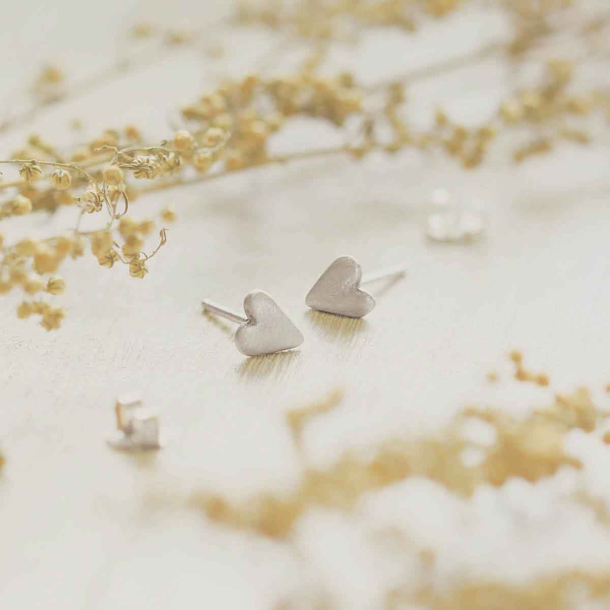 sterling silver tiny heart stud earrings with a matte brushed finish