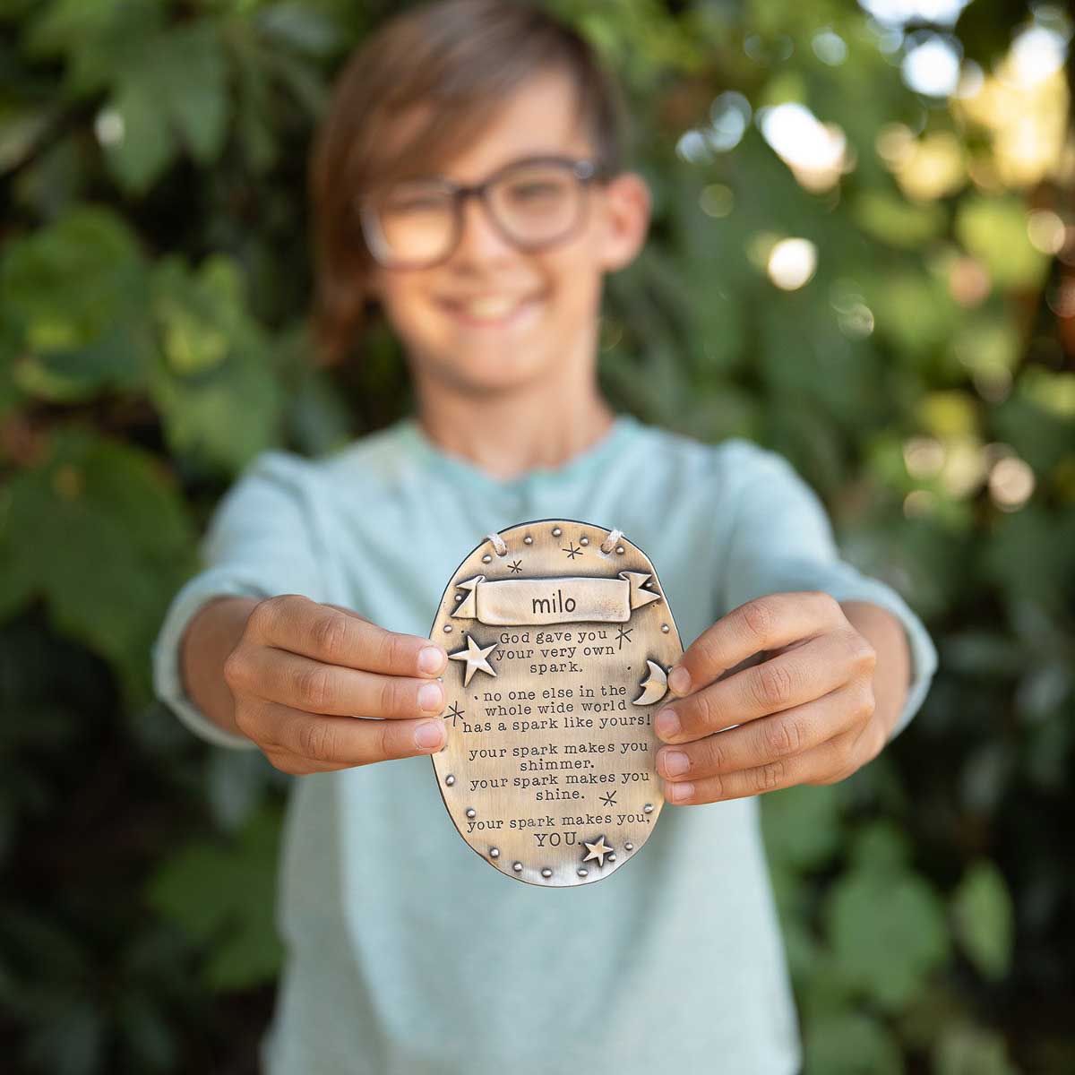 kid holding a pewter your spark plaque personalized with their name