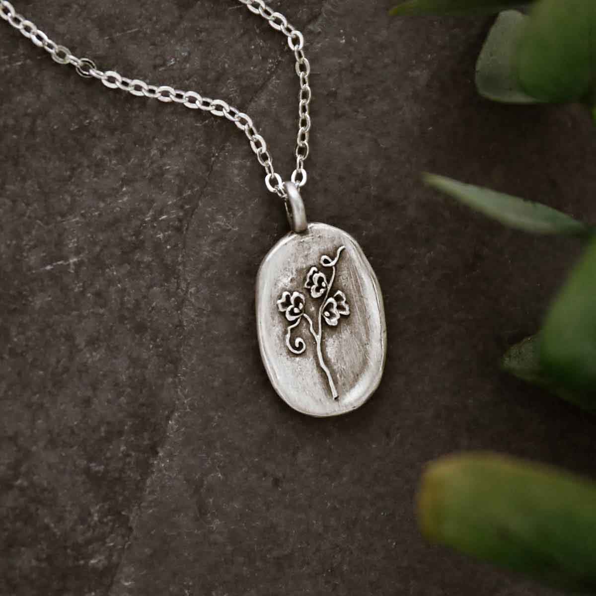 girl holding a pewter April Birth Flower necklace with 18" link chain