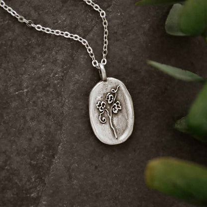 girl holding a pewter April Birth Flower necklace with 18" link chain