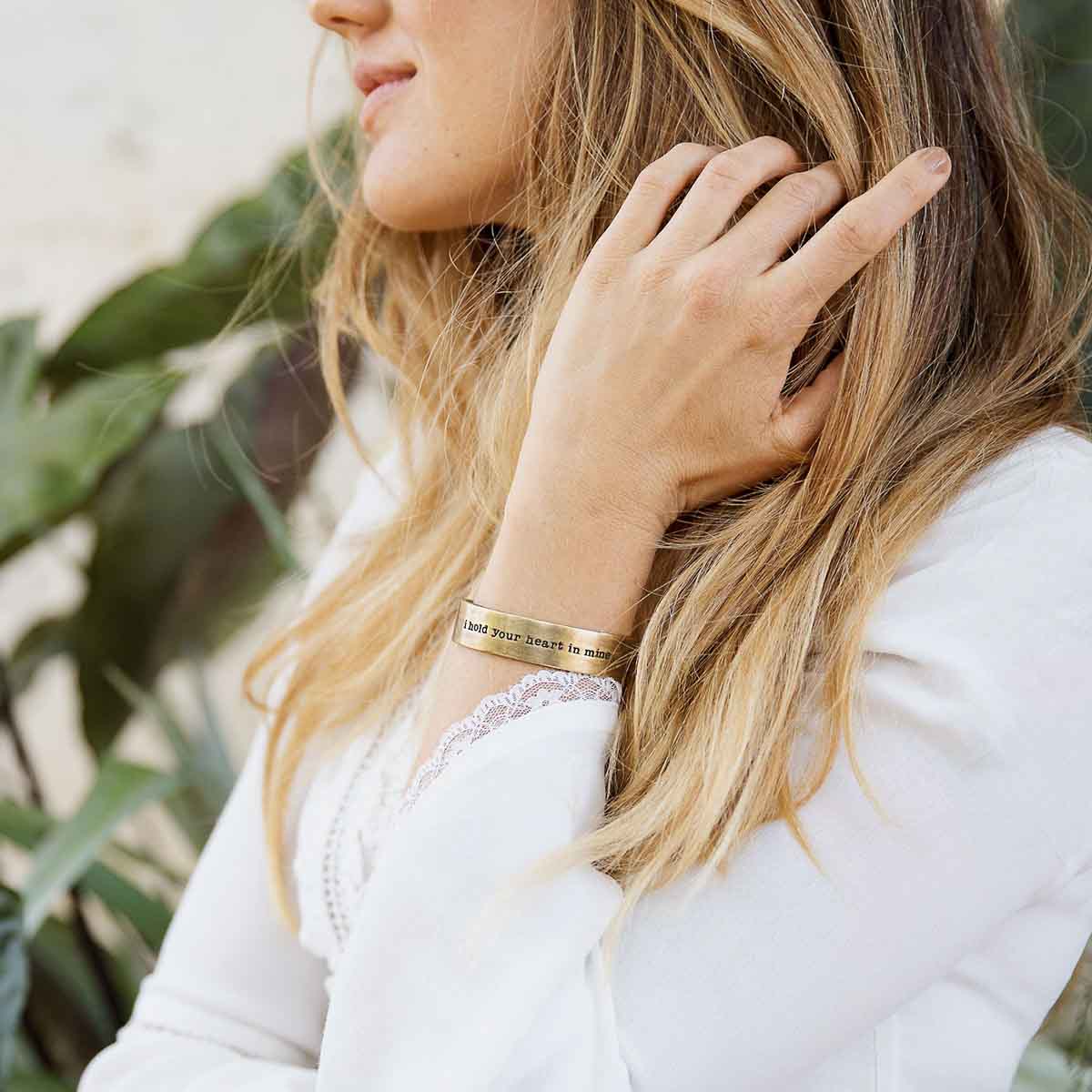 Girl wearing engraved artisan bronze-plated pewter I hold your heart cuff bracelet