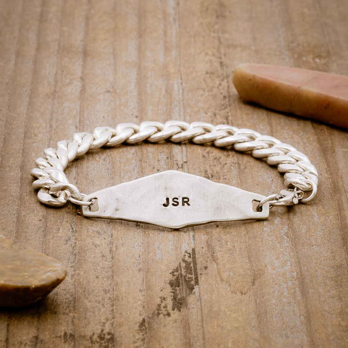 the sterling silver Identity Bracelet with a hand stamped personalized metal plate, on a wood background