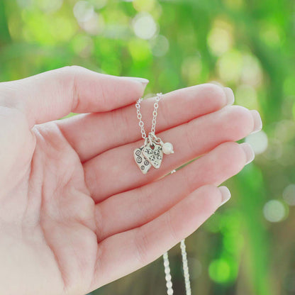 Light + Bright hearts necklace handcrafted in sterling silver with a matte brushed finish and the heart charm hung next to a vintage freshwater pearl