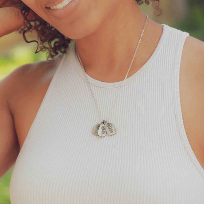 pewter Birth Flower necklace charms on beige background