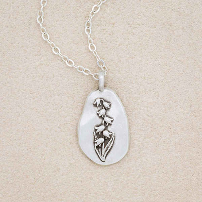 sterling silver May Birth flower necklace, on beige background