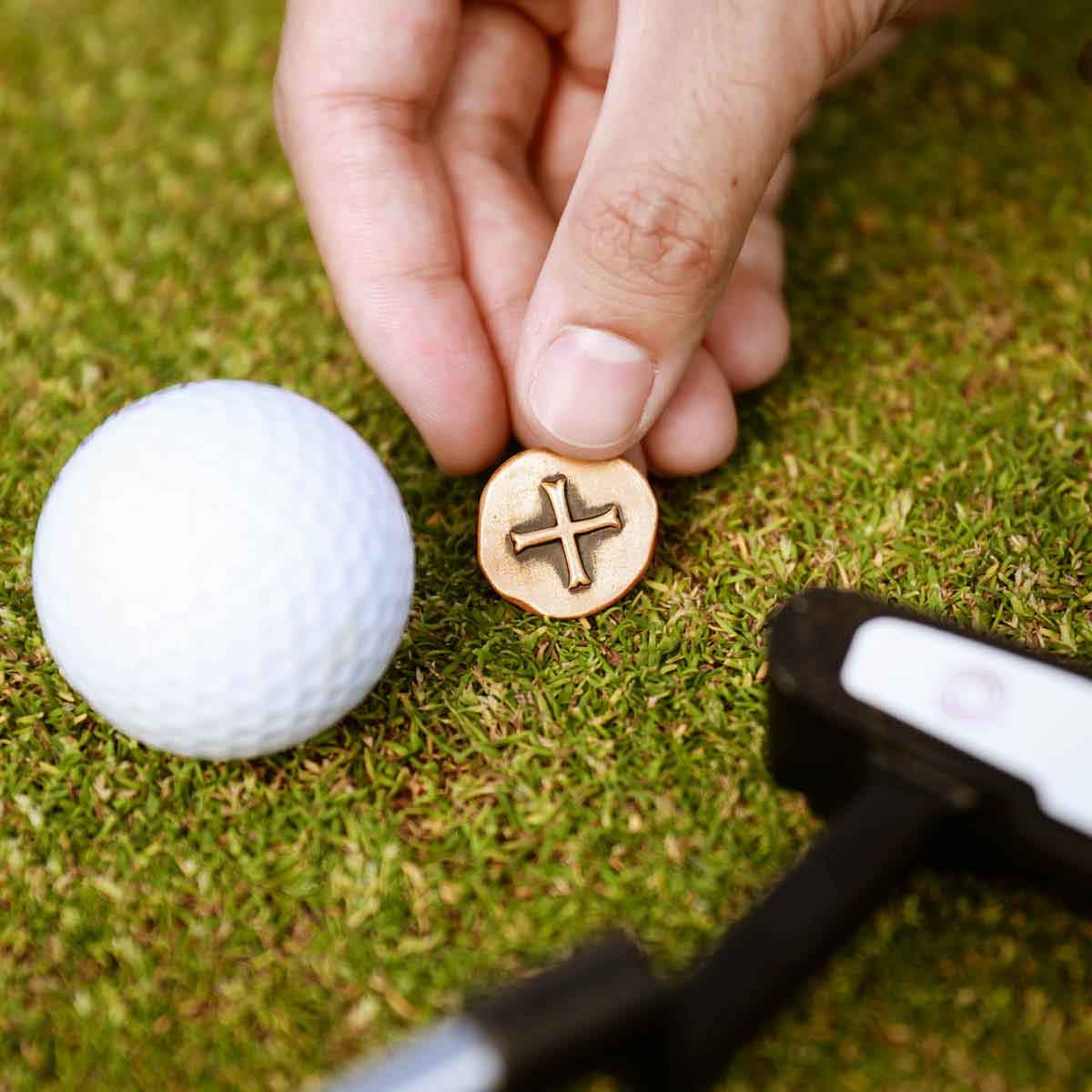 hand holding Bronze Roman Cross Coin Golf Ball Marker