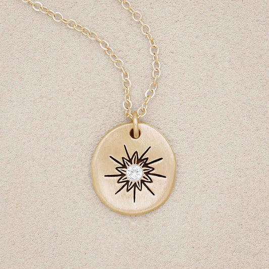 14k yellow gold sunburst diamond necklace on beige background