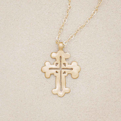 14k yellow gold work of art cross necklace, on beige background
